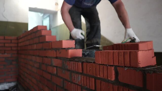 Bricklayer laying brick on cement mix on construction site close-up. Reduce the housing crisis by building more affordable houses
