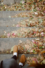 Feet descending steps amidst a carpet of vibrant fallen leaves.