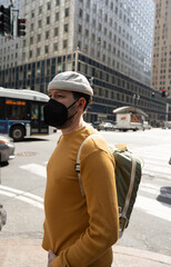 Cautious man in mask observes before crossing city street