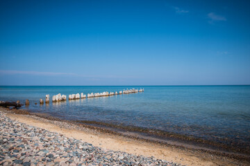 Clear blue waters of Lake Superior, with rocky beach and wooden pier.