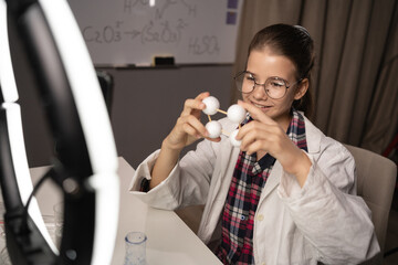 A child recording a video for a blog showing a molecular model on a mobile phone camera broadcasts live at home