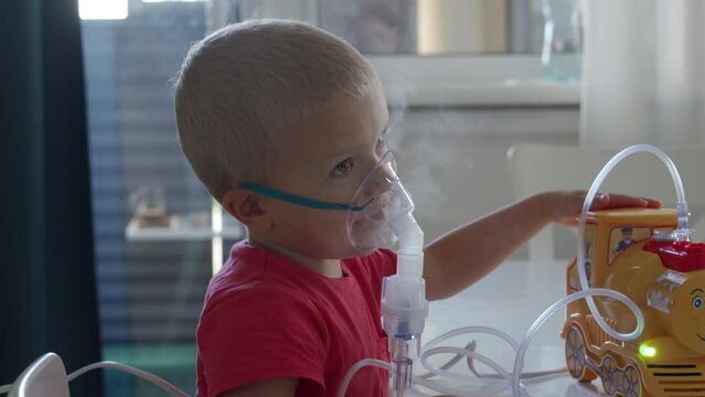Sick toddler child doing inhalation at home, little boy using nebulizer