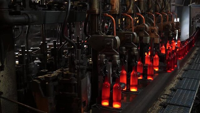 Automated line for the production of glass containers. The hot bottles are put on a moving conveyor. factory shop for the production of glass bottles and beverage. Glass recycling.
