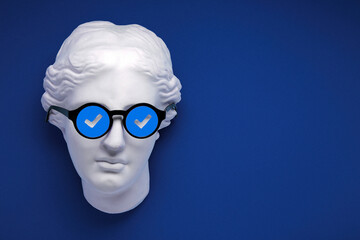 Verified badge or blue check sign concept collage. Plaster greek statue replica on blue background...