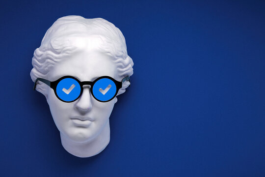 Verified badge or blue check sign concept collage. Plaster greek statue replica on blue background with funny face sunglasses