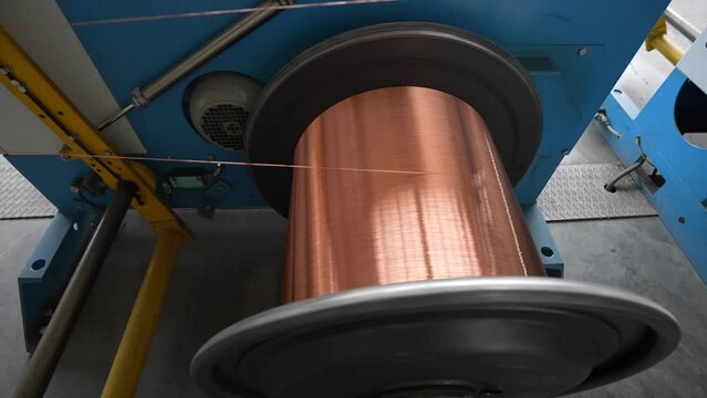 Copper wire cable production in coils, metal steel industrial plant. Metal wire spool spins on the machine. Inside the new factory manufacturing electrical cable. Cable production.
