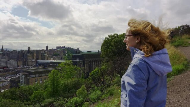 Woman enjoying views of Edinburgh from a hill in the city, Scotland.