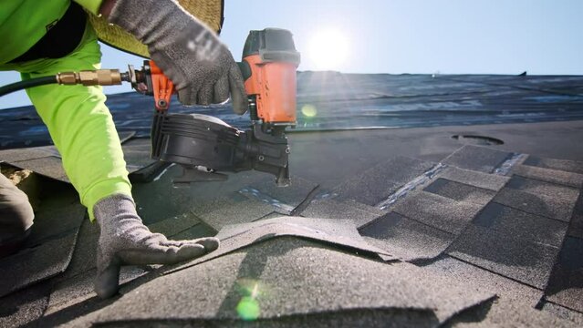 Close up footage of Roofer repair or replace shingle that has been damaged and needing replacement at sunny day. 