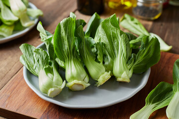 A group of cantonese vegetables on a plate on cutting board put on wooden table background.