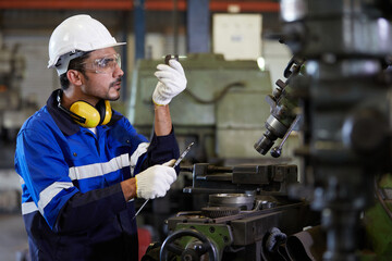 factory worker or technician looking and checking screw beside lathe machine in the factory