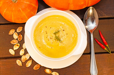 Pumpkin hot puree soup on a wooden table