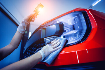 Car detailing worker cleaning and polishing car with microfiber cloth and vacuum.