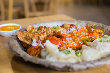 A plate of assorted chicken momos (steamed, fried and chilli sauce dumplings) served on a leaf plate at Tapari Nights, a Nepalese restaurant in Auburn, Sydney - NSW, Australia
