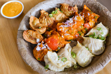 A plate of assorted chicken momos (steamed, fried and chilli sauce dumplings) served on a leaf plate at Tapari Nights, a Nepalese restaurant in Auburn - obrazy, fototapety, plakaty