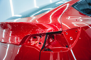 The process of installing protective film on the new red car.