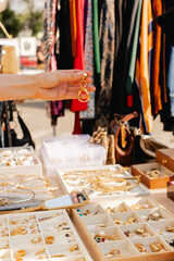 Female shopper picks out a handcrafted jewelry from a collection on a market stall. Small business and travel shopping experiences concept. Close-up. Selective focus