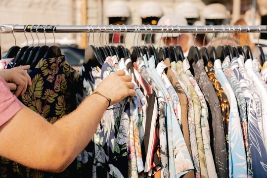 Choice of fashion clothes of different colors on hangers in a retail shop. Flea market with old clothes outside. Reduce Reuse Recycle concept