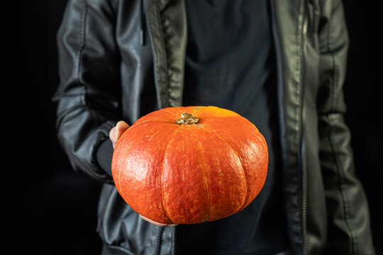Beautiful pumpkin in male hahd on black background. Minimalism. Vegetable, organic food concept