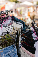 Naklejka premium Choice of fashion clothes of different colors on hangers in a retail shop. Flea market with old clothes outside. Reduce Reuse Recycle concept