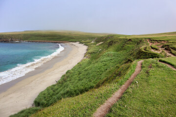 Blue water white sand scottish beach in scotland with grass and dunes