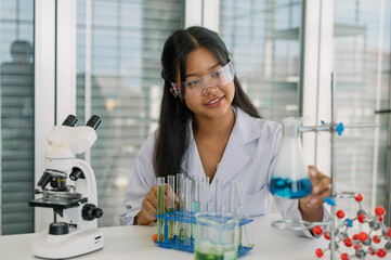 Asian girl student learning and doing chemical experiment in science class. Cute teenager female...