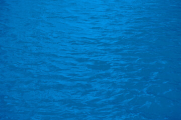 Obraz premium Defocus blurred transparent blue colored clear calm water surface texture with splashes reflection. Trendy abstract nature background. Water waves in sunlight with copy space. Blue watercolor shine.