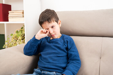 Close up of child scratching itchy eye at home