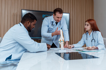 Fototapeta premium A team of orthopedic specialists, men and women of various nationalities, wore uniforms. X-ray film and graphic projector screen