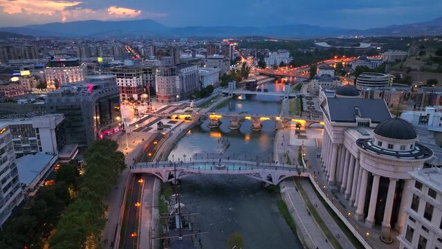 Night aerial view of Skopje - capital of North Macedonia. Bridges, Vardar river and city center in the evening lights. 
