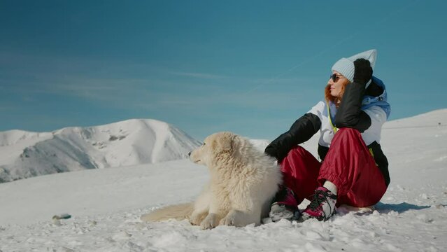 Female explorer petting her dog while admiring surroundings in the mountainsin winter. Best friendish ever human and the dog.