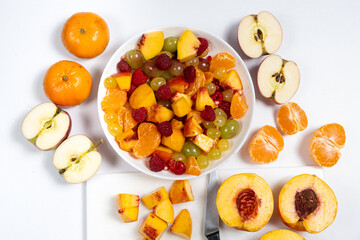 Cooking a fruit salad from an assortment of fruits and berries - cutting the nectarine into pieces