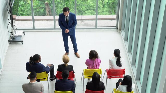 middle eastern business man standing and talking in font of group of diversity business people in meeting at seminar. speaker giving lecture at a business seminar