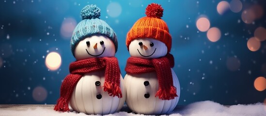 Two cute snowmen dressed in scarves and hats, smiling on a blue background in defocus. Abstract...
