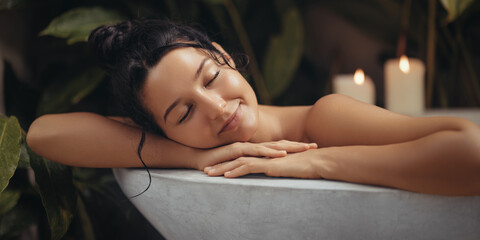 Home spa relax of bathing beauty woman resting in bathtub with closed eyes. Close-up portrait of attractive millennial woman relaxing in modern bathroom interior, happy lady enjoying taking hot bath