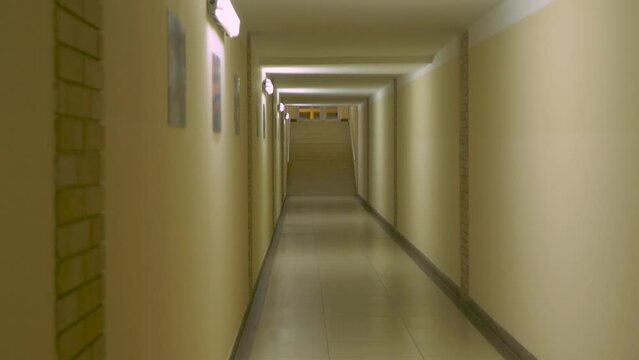 Long empty light corridor or hall. Yellow wall at hospital, school or hotel. Indoor built structure