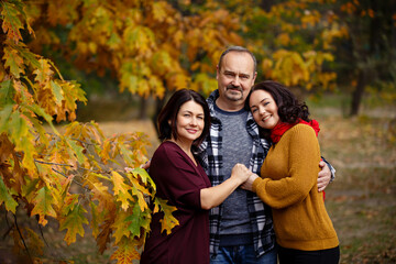 autumn portrait of middle-aged parents and their adult daughter on a walk outdoors. Family of respectable age in autumn park. Happy family story. Together during all their life. Warm autumn sunny days