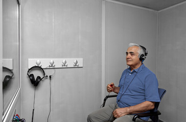 Audiologist woman doing the hearing exam to a mixed race man patient using an audiometer in a...