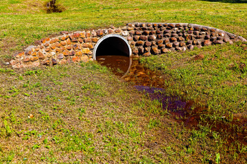 Description
Concrete culvert forming a grassy bridge over a drainage ditch with rock cladding near Riversdale in the Western Cape, South Africa - obrazy, fototapety, plakaty