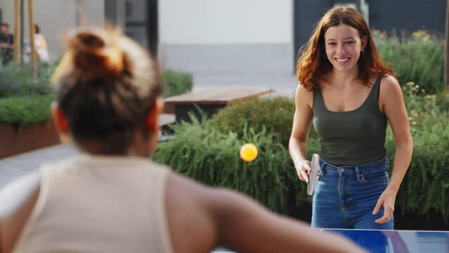 Cheerful young women friends playing ping pong table tennis, having fun together