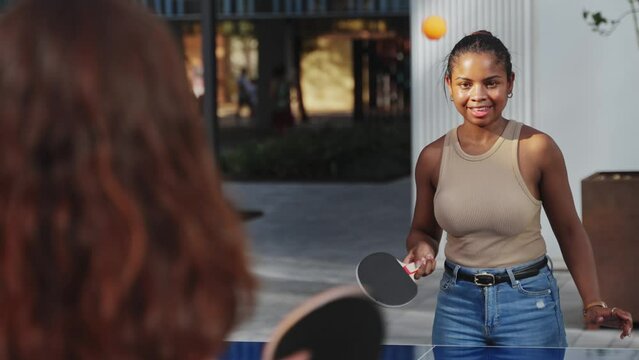 Young women playing ping pong table tennis, having fun together