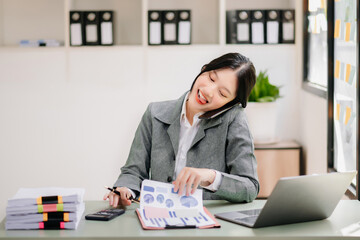 Successful Asian Businesswoman Analyzing Finance on Tablet and Laptop at Office Desk tax, report, accounting, statistics, and analytical research concept.