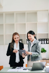 Businesswomen work and discuss their business plans. A Human employee explains and shows her colleague the results paper in office..