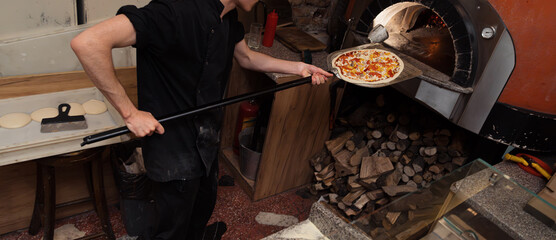 Pizza concept. Preparing traditional italian pizza. Long shovel for pizza, baking dough in a...