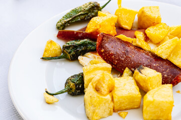 Close-up of a traditional Spanish meal with grilled sausages and vegetables.