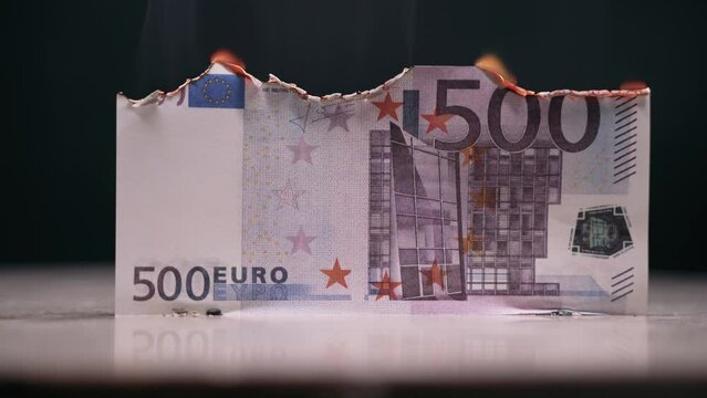 The euro is slowly smoldering. Cash is not used in everyday life. The euro is falling. The 500 euro bill is slowly smoldering from the fire.