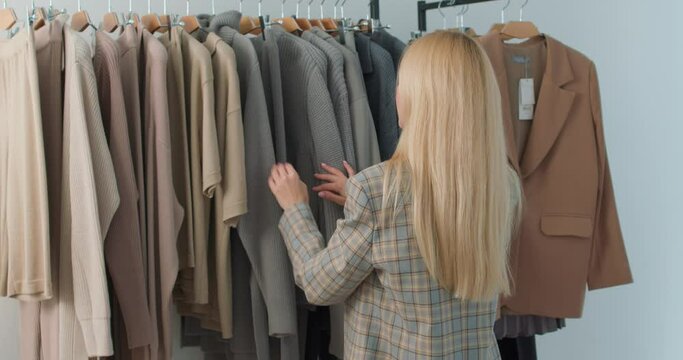 personal stylist selects clothes in store Beautiful fashion stylist lady selecting clothing for client. Girl doing shopping in mall Slow motion shop assistant help customers to look fashionable Style.