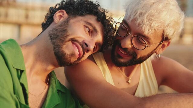 Close-up of romantic gay couple talking while sitting on the beach