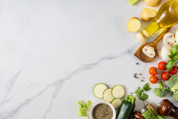 Healthy food cooking ingredients background with fresh vegetables, herbs, spices and olive oil on marble table with copy space top view