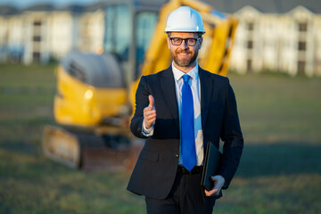 Builder engineer or civil engineer worker at a construction site. Engineer worker in suit and helmet at construction site. Supervisor construction manager near excavator. Renovation building concept.