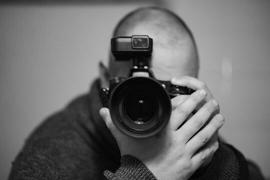 A man photographer takes pictures directly into the camera. Black and white image